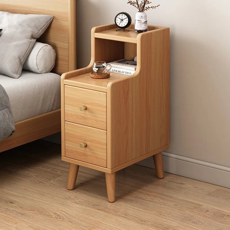 Narrow oak bedside table with two drawers and an open shelf beside a bed