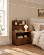 Narrow walnut bedside table beside a linen bed in a British bedroom with a sash window
