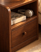 Close-up of the open cubby, drawer and round wooden knob in walnut-tone grain