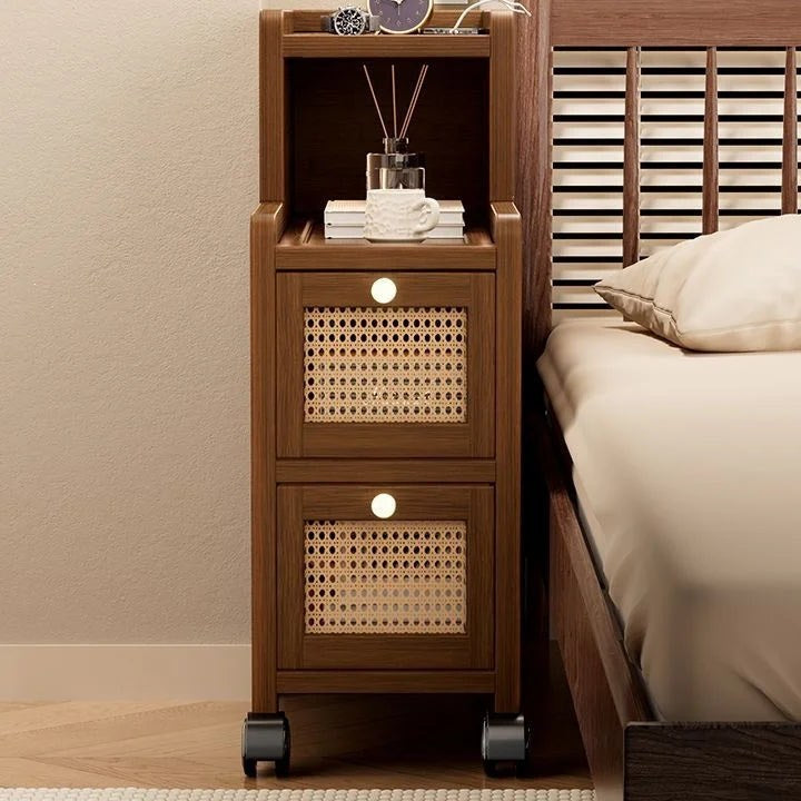 Narrow walnut bedside cabinet with two rattan drawers beside a bed