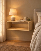 Natural wood floating bedside shelf with a lamp switched on and an open book in the evening