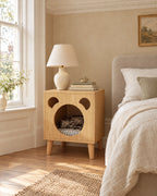 Oak bear bedside table with a cat asleep in the nook, in a British bedroom with a sash window