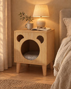 Oak bear bedside table with a pet nook, lamp switched on and an open book in the evening