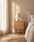 Oak bedside table with brass knobs and a ceramic lamp in morning light