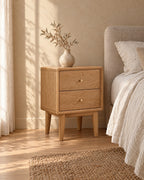 Three-quarter view of the oak bedside table showing its tapered legs