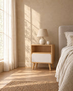 Oak-effect bedside table with open niche and white drawer in warm morning light with window shadows on the wall