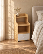 Three-quarter view of the oak-effect bedside table with open shelves and a lockable drawer