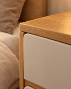 Close-up detail of the oak and cream bedside table with two handle-free drawers