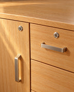 Close-up of the key locks and brushed-steel handles on the oak door and drawer