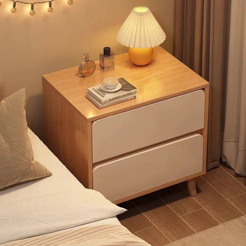Oak and white bedside table with two drawers beside a bed