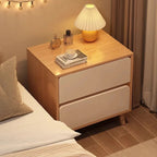 Oak and white bedside table with two drawers beside a bed