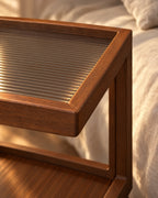 Close-up detail of the walnut-effect rolling bedside table with three open tiers