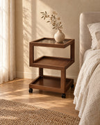 Three-quarter view of the walnut-effect rolling bedside table with three open tiers