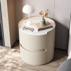 Round cream bedside table with a marble-effect top in a bedroom