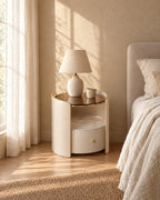 Round cream bedside table with glass top in morning light