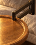 Close-up of the raised rim of the round wood-effect top and the hinge of the black swing arm