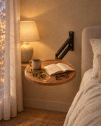 Round wall-mounted bedside table with wood-effect top fixed to the wall with a lamp switched on and an open book in the evening