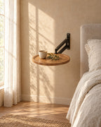 Round wall-mounted bedside table with wood-effect top in warm morning light with window shadows on the wall