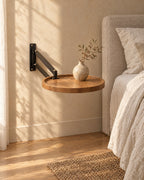 Three-quarter view of the round wall-mounted bedside table with wood-effect top, fixed to the wall with nothing underneath
