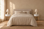 Pair of round white bedside tabless with natural wood legs on each side of a double bed