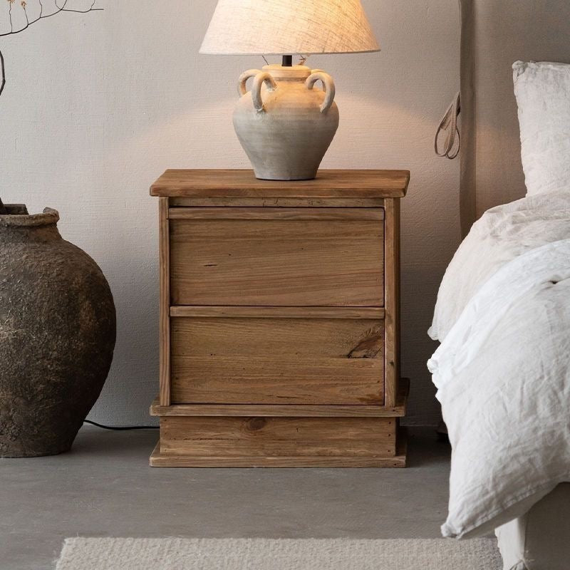 Rustic wood bedside table on a plinth base in a bedroom