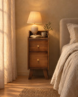 Slim walnut-finish bamboo bedside table with a lamp switched on and an open book in the evening