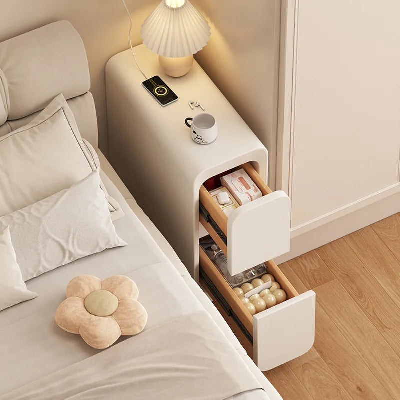 Slim cream bedside table with both drawers open beside a bed