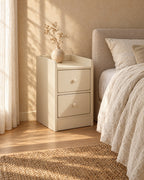 Three-quarter view of the slim cream bedside table showing its depth and plinth