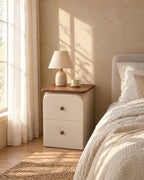 Slim cream bedside table with walnut-effect top and two drawers with wooden knobs with a ceramic lamp in morning light