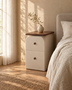 Three-quarter view of the slim cream bedside table with walnut-effect top and two drawers with wooden knobs