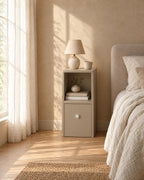 Slim greige bedside table with open shelf with a ceramic lamp in morning light