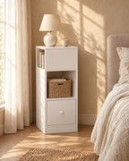 Slim white bedside table with an open shelf and a drawer in morning light