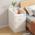 Slim white bedside table with two drawers next to a bed