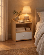 Small oak and white bedside table, lamp switched on and an open book in the evening