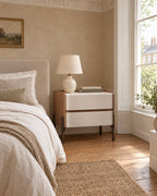 Tan and ivory bedside table beside a linen bed in a British bedroom