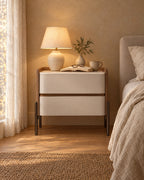 Tan and ivory bedside table with a lamp switched on in the evening