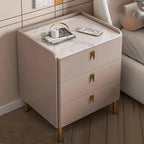 Taupe bedside table with three drawers and a stone top beside a bed