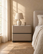 Taupe faux leather bedside table with a ceramic lamp in morning light