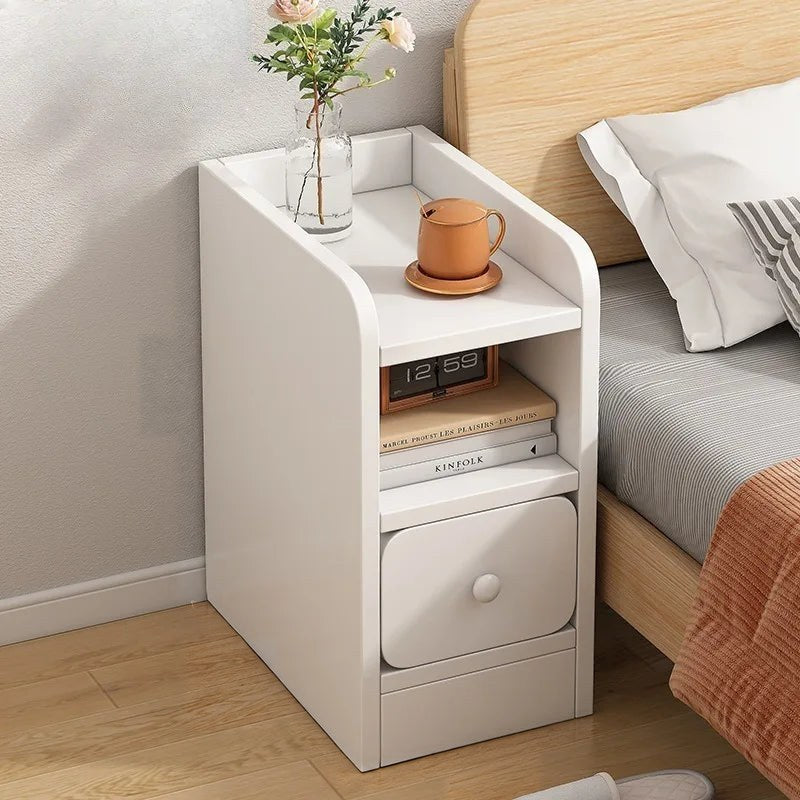 Ultra-narrow white bedside table with a drawer and an open shelf beside a bed