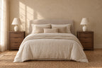 Two walnut bedside tables with three drawers and carved finger pulls on each side of a double bed
