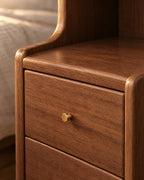 Close-up of the brass knob and walnut grain of the top drawer