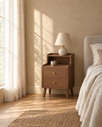 Walnut bedside table with brass knobs and a ceramic lamp in morning light