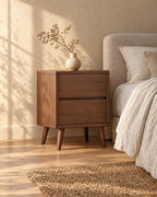 Three-quarter view of the walnut bedside table showing the tapered legs