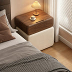 Walnut and cream bedside table with a pleated lamp beside a bed