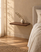 Three-quarter view of the walnut floating bedside shelf, fixed to the wall with nothing underneath
