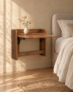 Three-quarter view of the walnut-tone fold-down wall-mounted bedside cabinet, fixed to the wall with nothing underneath