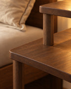 Close-up of the walnut tabletop corner, round leg and raised shelf post