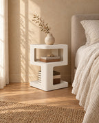 Three-quarter view of the white bedside table showing its three open tiers