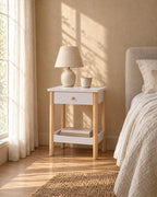 White bedside table with a drawer and lower shelf in morning light