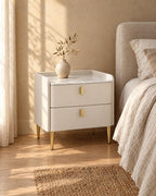 Three-quarter view of the white bedside table showing the slim gold legs